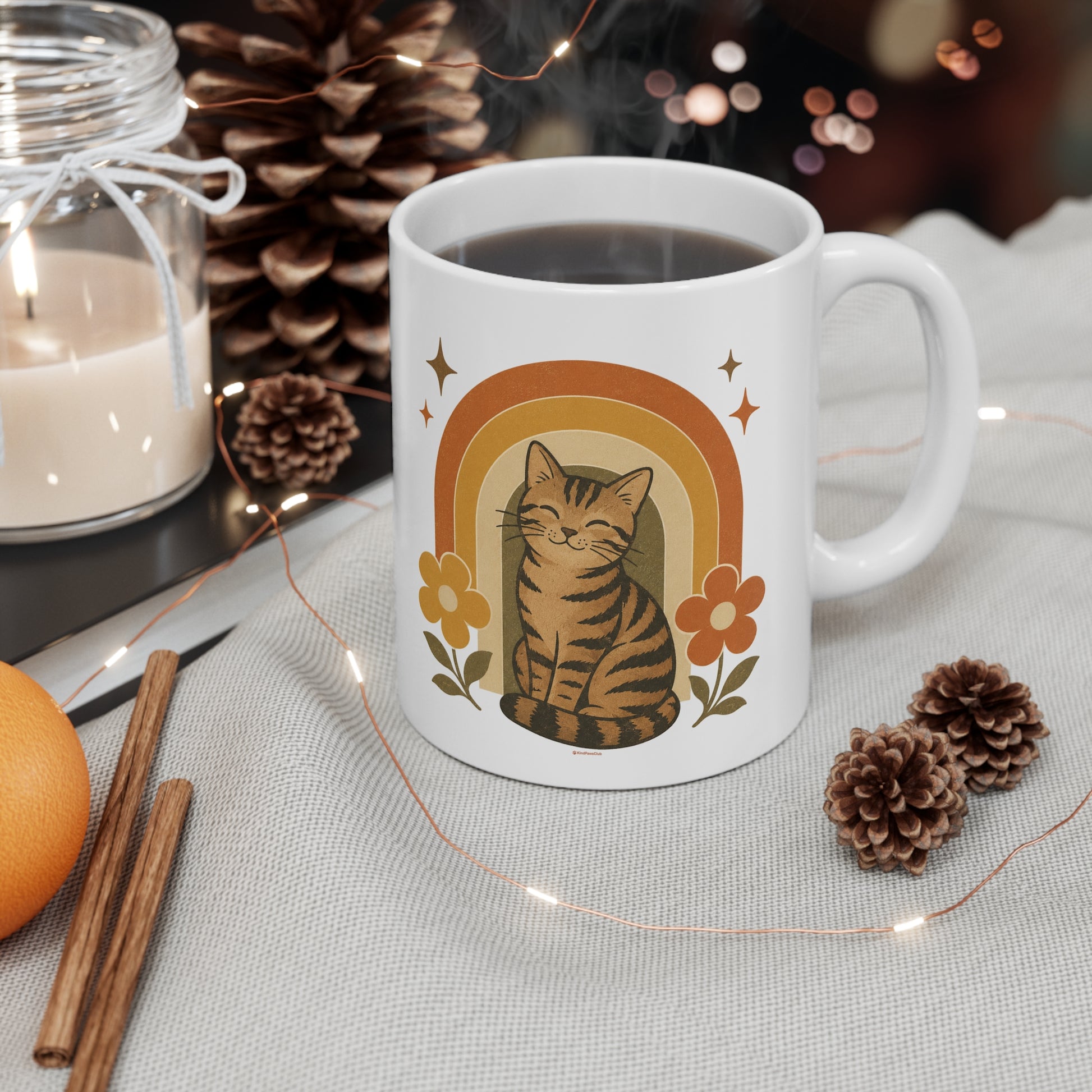 White mug with a cat illustration on a table with decorative items