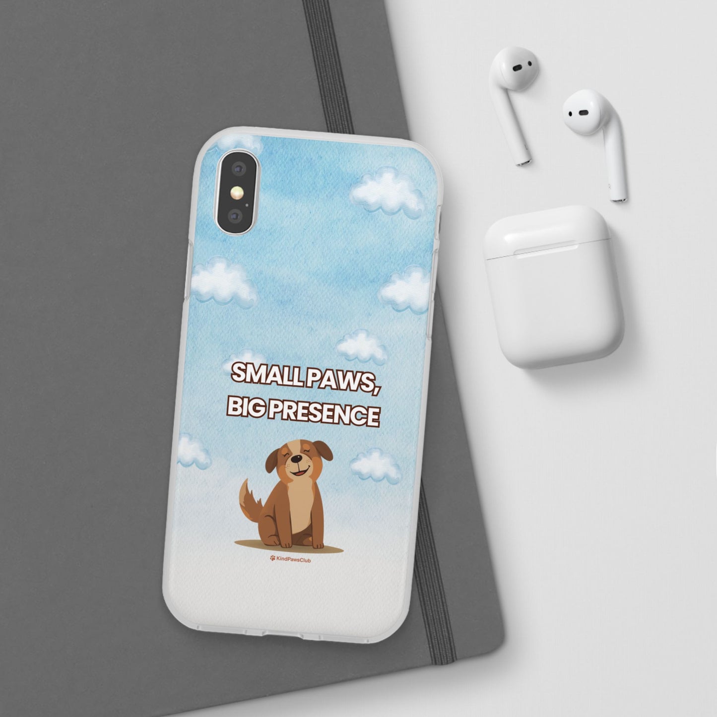 Phone case with a dog illustration and text 'Small Paws, Big Presence' on a blue sky background, next to earbuds and a white case.